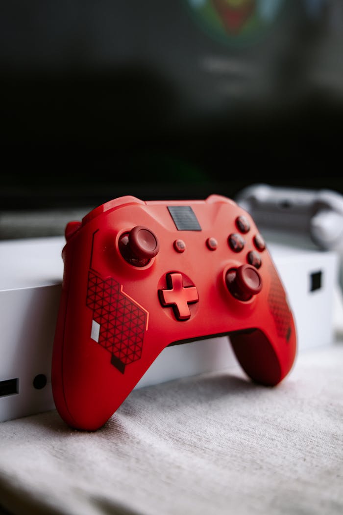 Close-up of a red gaming controller resting on a white console, perfect for tech enthusiasts.