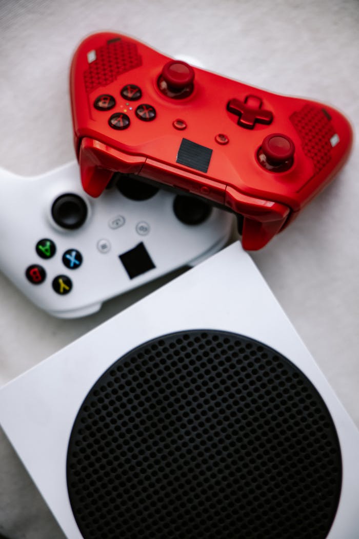 Vertical shot of vibrant red and white game controllers on a modern console.